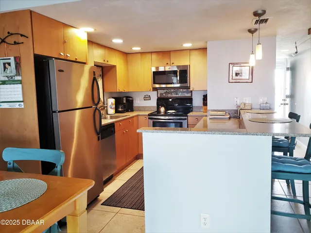 a kitchen with stainless steel appliances a refrigerator a sink a stove a microwave a dining table and chairs