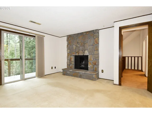 a view of an empty room with a fireplace and a window