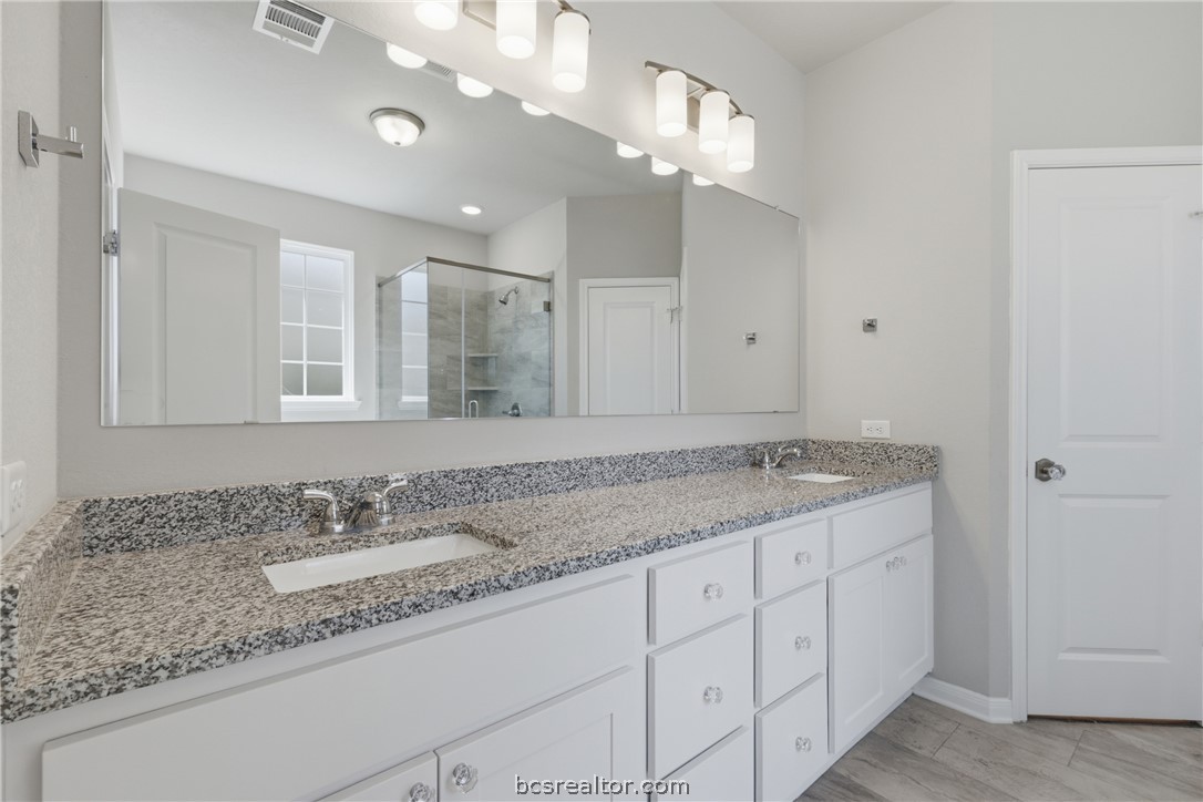 1922 Viva Road Bryan, TX 77807 - Photo 18 of 45 Well-appointed primary bathroom offers granite countertops, dual vanities, a soaking tub, and walk-in shower.