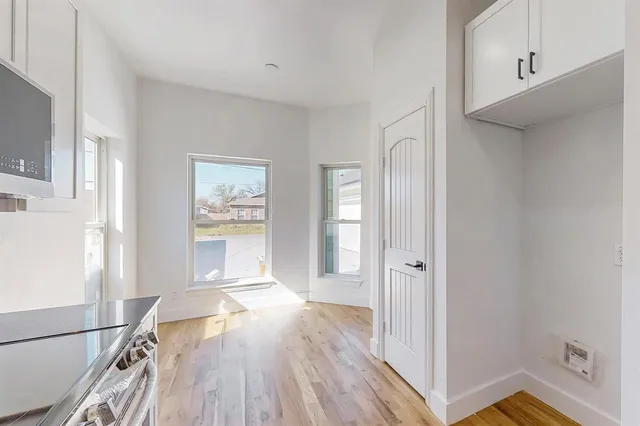 a view of a hallway with wooden floor and cabinet