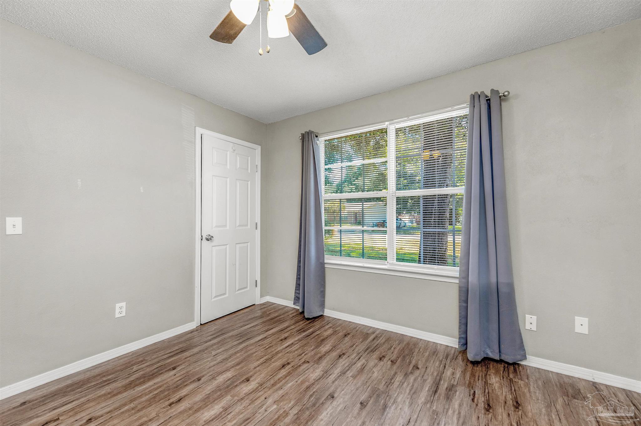 5499 Chantilly Circle Milton, FL 32583 - Photo 16 of 24 an empty room with wooden floor and windows