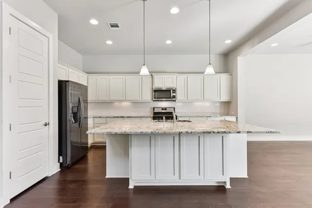 a kitchen with stainless steel appliances granite countertop a sink a stove and a refrigerator