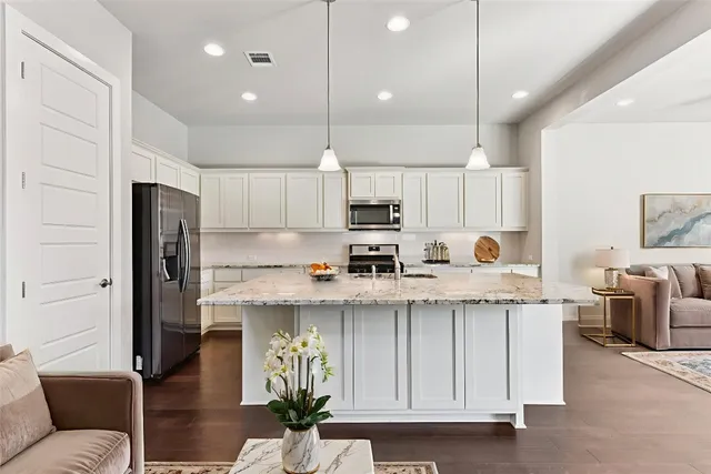 a kitchen with stainless steel appliances granite countertop a refrigerator a sink dishwasher a stove and white cabinets with wooden floor