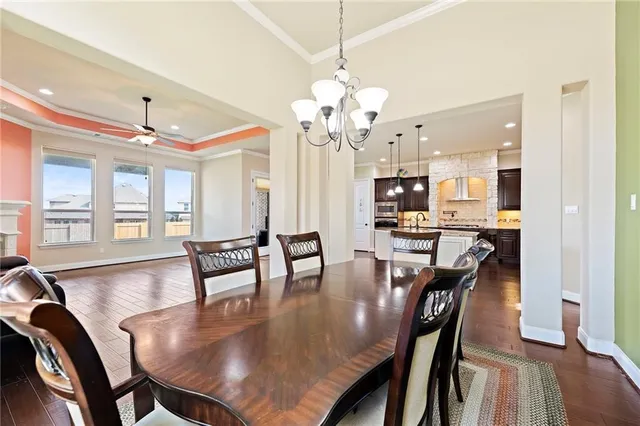 a dining room with wooden floor a chandelier a wooden table and chairs