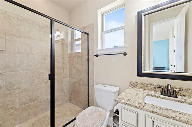 a bathroom with a granite countertop sink toilet a mirror and shower
