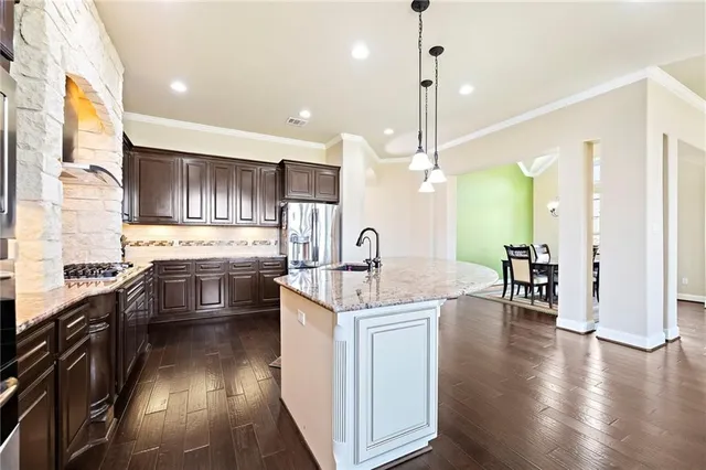 a kitchen with granite countertop a stove top oven a sink dishwasher a dining table and chairs with wooden floor