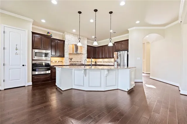 a large kitchen with stainless steel appliances kitchen island a large counter top and a wooden floors
