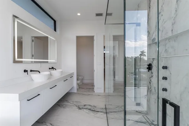 a bathroom with a double vanity sink mirror and shower