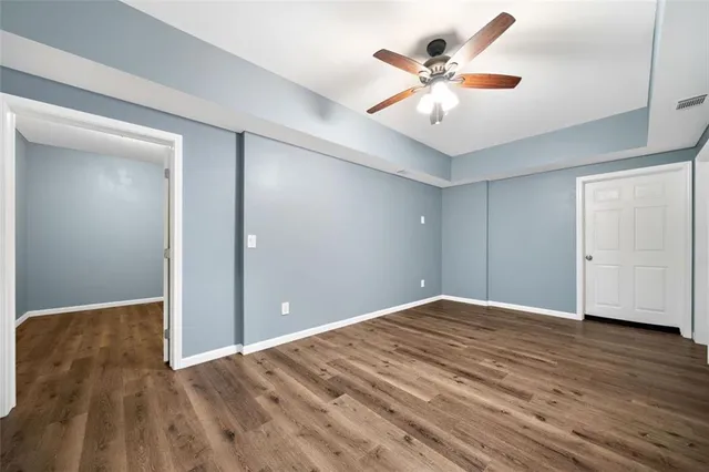 wooden floor in white room with a ceiling fan