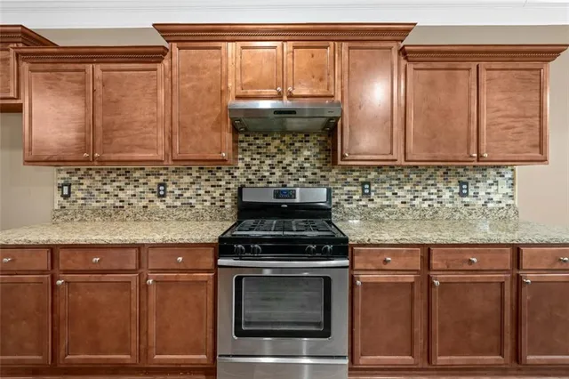 a kitchen with granite countertop a stove and cabinets
