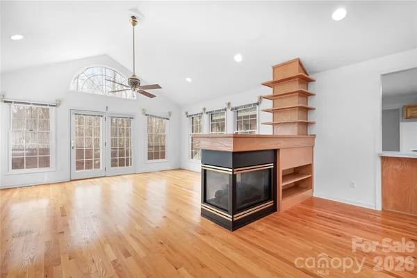 a living room with stainless steel appliances kitchen island granite countertop a stove a kitchen island a refrigerator and a wooden floors