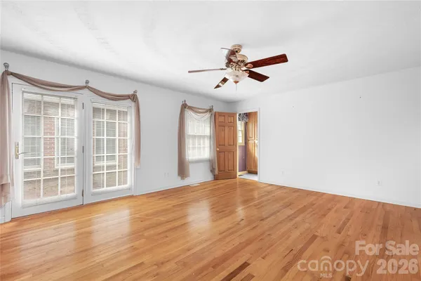 a view of an empty room with a window and wooden floor