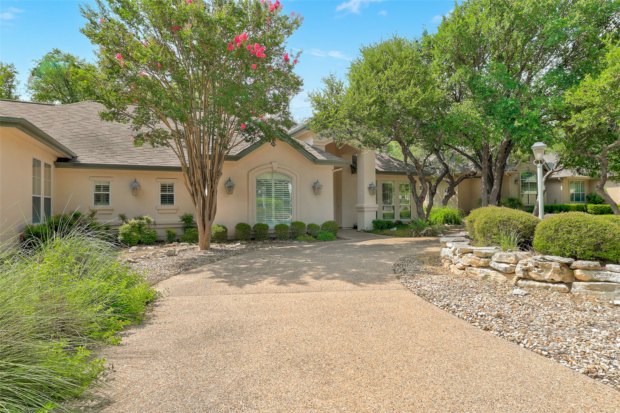33 Meadows End Georgetown, TX 78628 - Photo 5 of 40 A graceful driveway leads to a classic residence, framed by mature trees and verdant landscaping.
