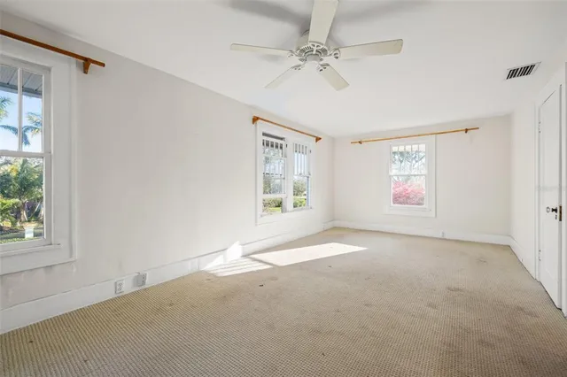 an empty room with windows and fan