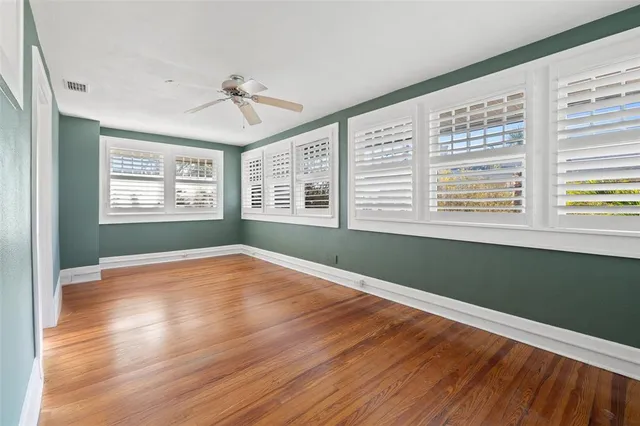 a view of empty room with wooden floor and fan