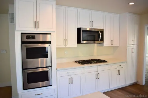 a kitchen with white cabinets and stainless steel appliances
