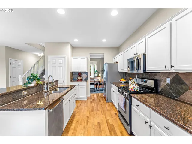 a large kitchen with stainless steel appliances granite countertop a lot of counter space and a sink