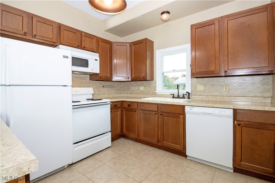 5699 Massillon Road Dalton, OH 44618 - Photo 6 of 24 Kitchen with decorative backsplash, sink, light tile patterned floors, and white appliances