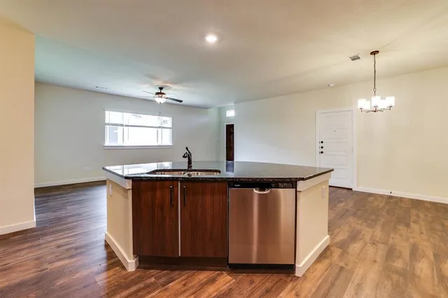 a kitchen with stainless steel appliances granite countertop a sink a stove a refrigerator and island with wooden floor