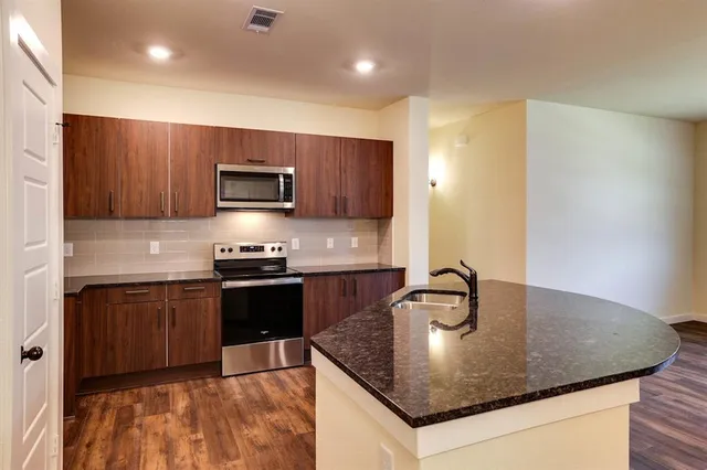 a kitchen with granite countertop a sink and a stove top oven with wooden floor