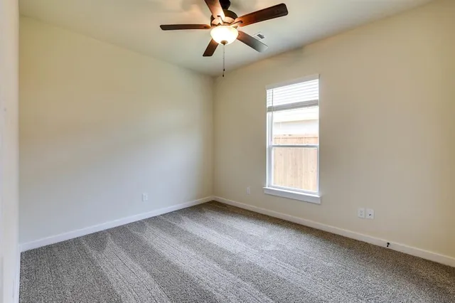 an empty room with a window and a fan