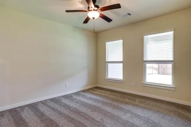 a view of empty room with window and ceiling fan