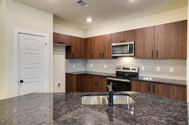 a kitchen with granite countertop a stove a sink and a microwave