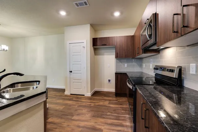 a kitchen with stainless steel appliances granite countertop a sink a stove and a refrigerator