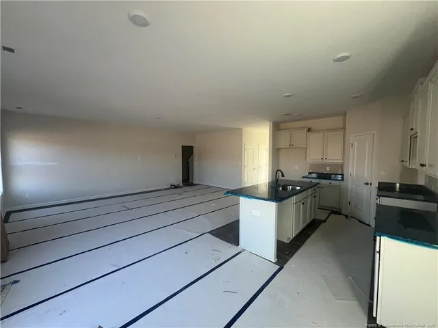 a view of kitchen and empty room with windows