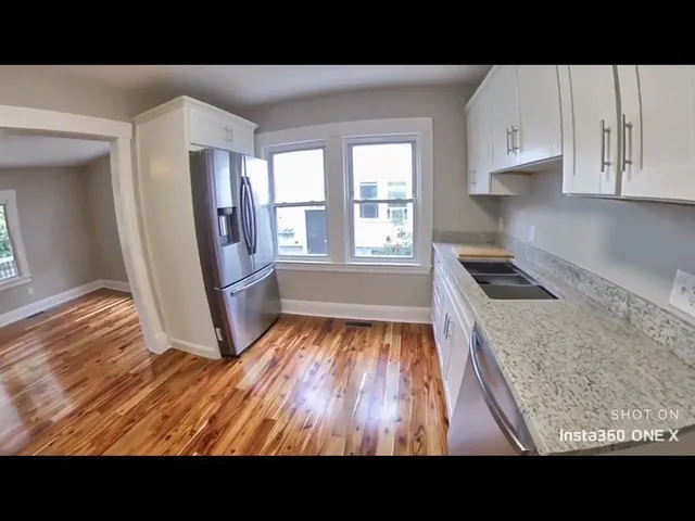 a view of an empty room with kitchen and a window