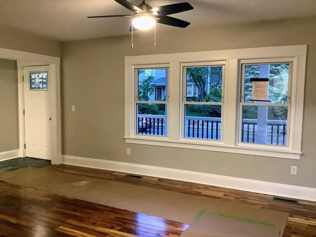 a view of an empty room with a window and wooden floor