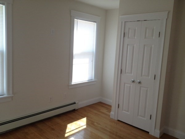 200 Brooks Street, Unit 1 Boston, MA 02128 - Photo 4 of 10 an empty room with wooden floor and windows
