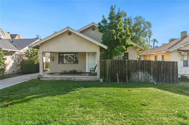 a view of a house with a small yard and a large tree