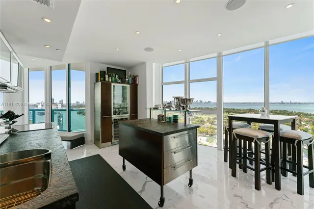 a kitchen with stainless steel appliances granite countertop a stove top oven a dining table and chairs with wooden floor