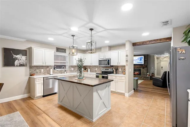 a kitchen with stainless steel appliances granite countertop a refrigerator oven a sink dishwasher and white cabinets with wooden floor