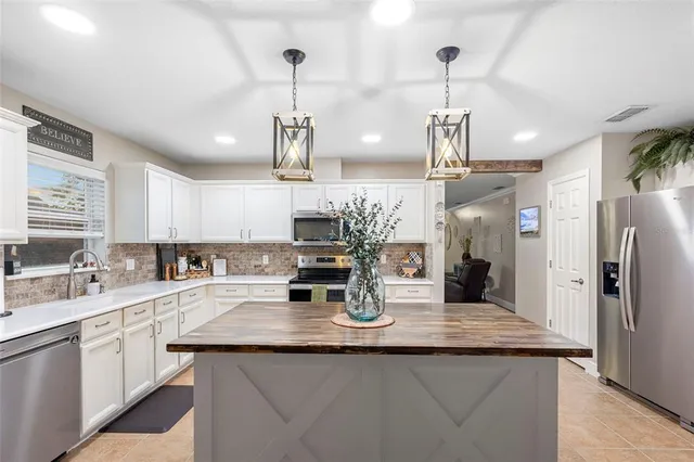 a kitchen with stainless steel appliances kitchen island granite countertop a sink and refrigerator