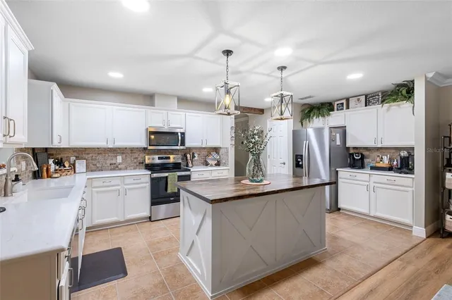 a kitchen with kitchen island granite countertop a sink cabinets and stainless steel appliances