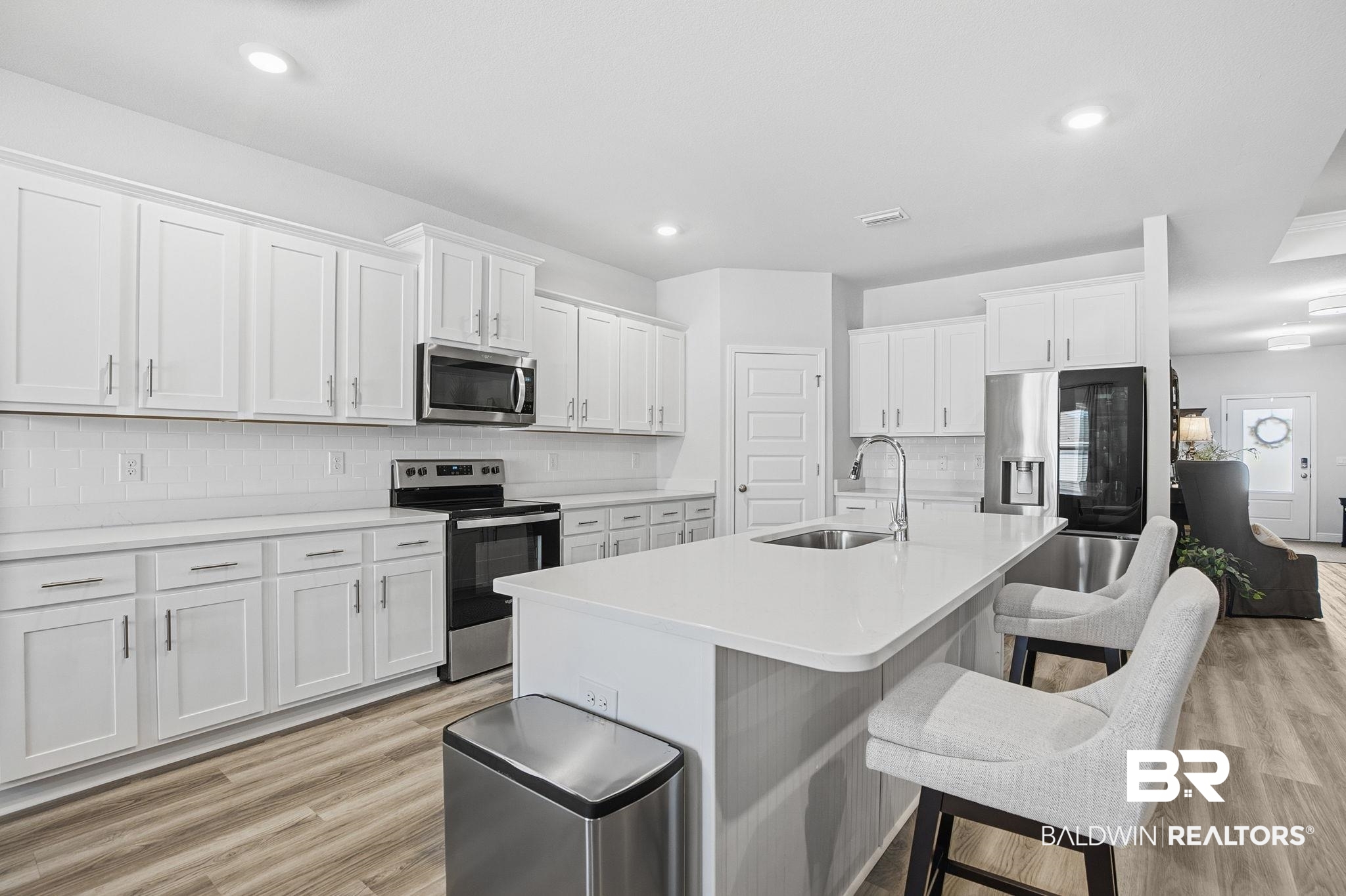 11123 Genuine Risk Circle Daphne, AL 36526 - Photo 17 of 67 Kitchen featuring stainless steel appliances, white cabinets, a kitchen bar, tasteful backsplash, and an island with sink