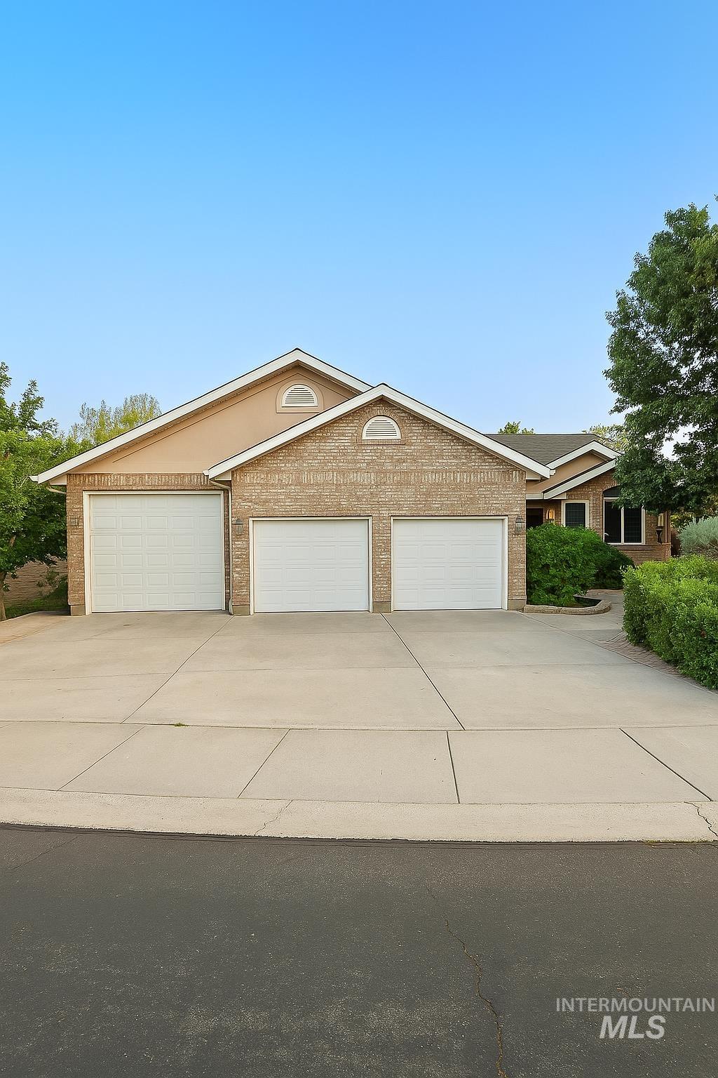 View of front of home with concrete driveway, an attached garage, and brick siding