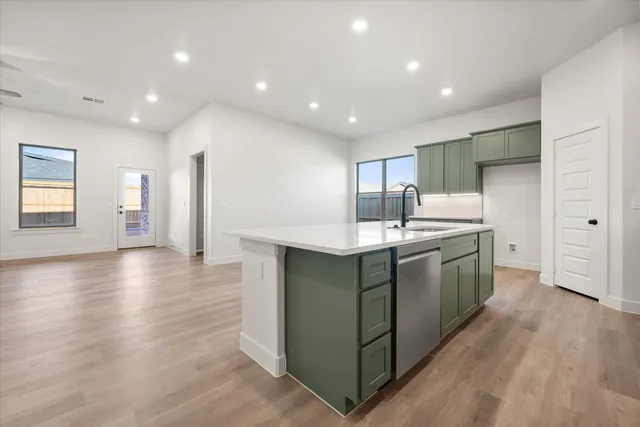 a kitchen with stainless steel appliances granite countertop a sink a stove a refrigerator and island with wooden floor