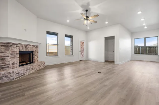 an empty room with windows and fireplace