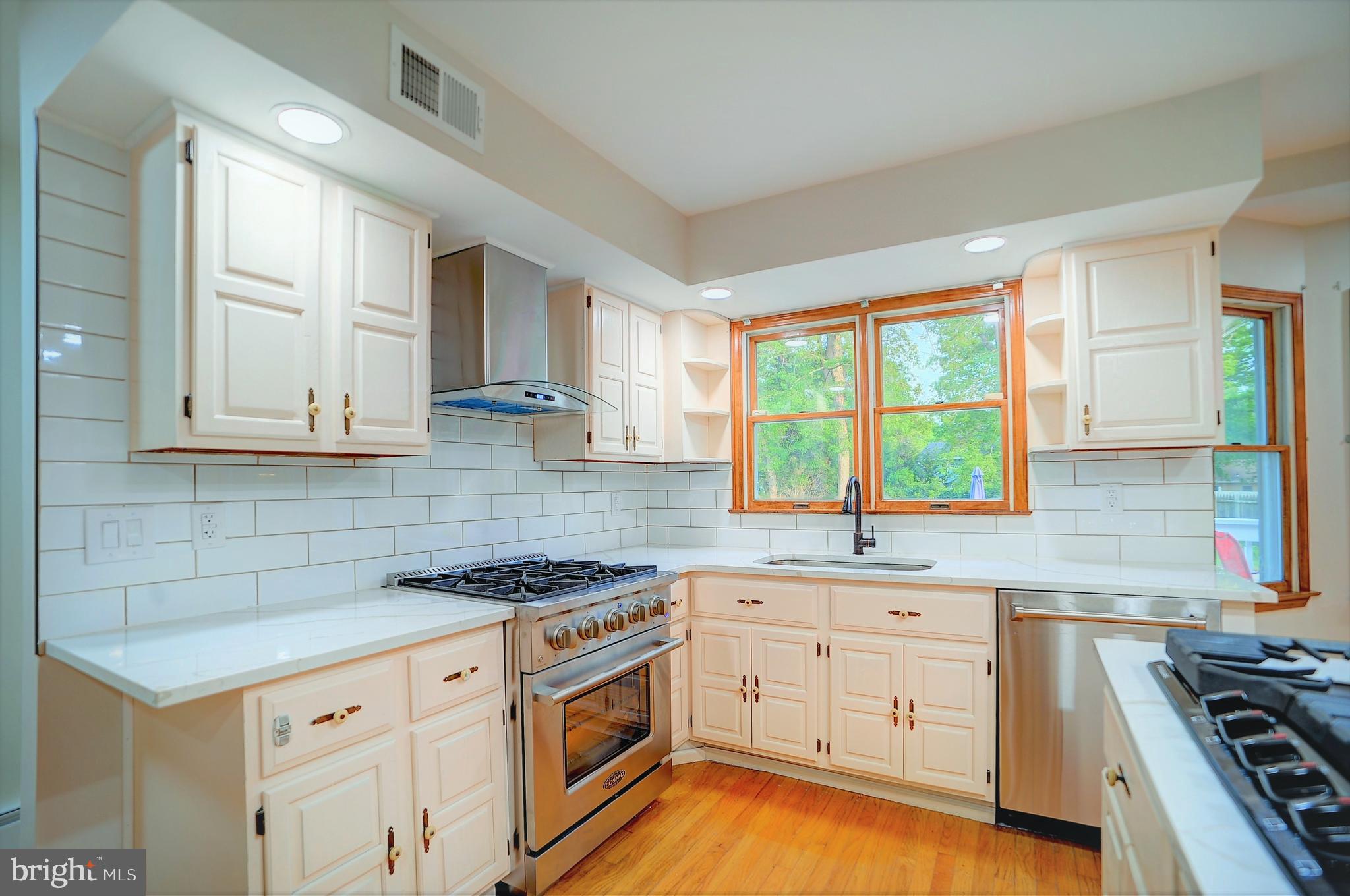 705 Princeton Road Lanoka Harbor, NJ 08734 - Photo 31 of 141 a kitchen with granite countertop a stove a sink dishwasher and white cabinets with wooden floor