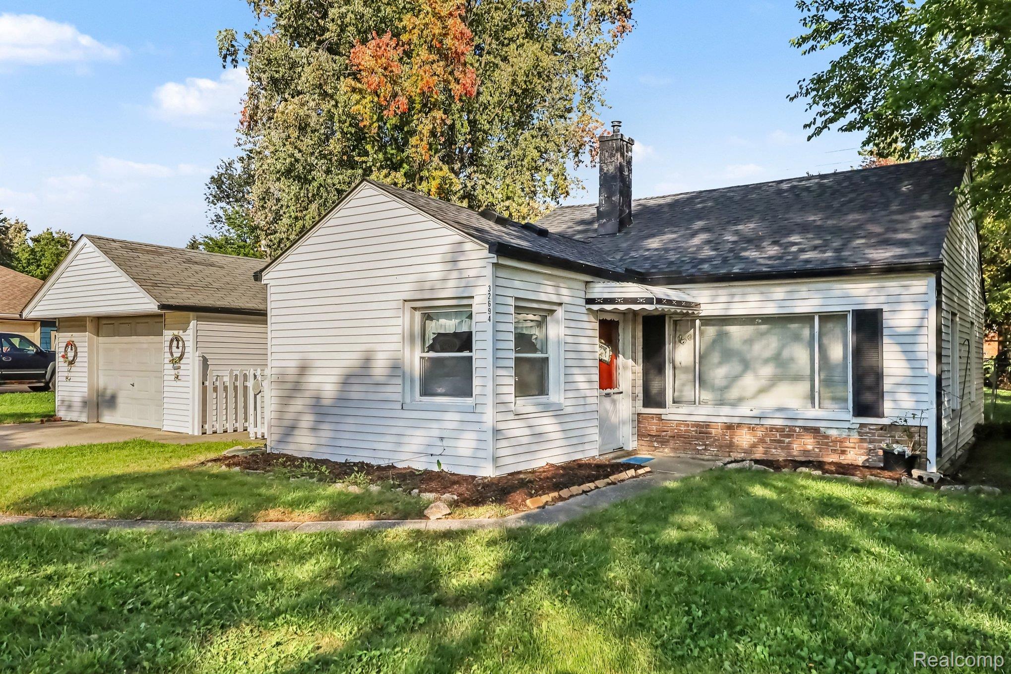 32694 Ruehle Avenue Warren, MI 48093 - Photo 3 of 15 Single-story residence featuring white siding, a dark asphalt shingle roof, and a prominent brick chimney