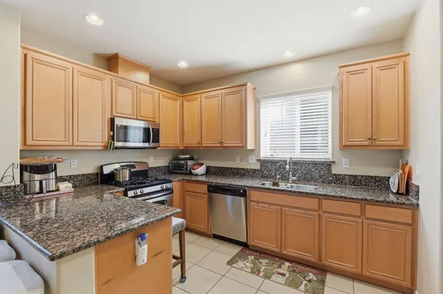 a kitchen with stainless steel appliances granite countertop a stove a sink and a microwave
