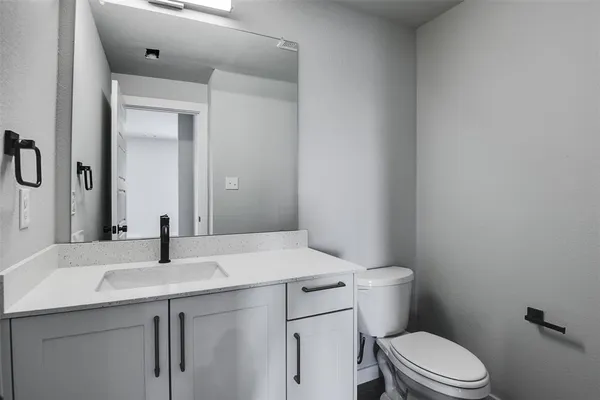 a bathroom with a sink vanity mirror and toilet