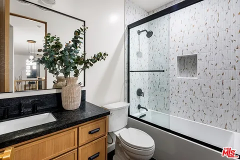 a bathroom with a granite countertop sink a toilet and shower