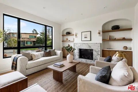 a living room with furniture fireplace and a large window