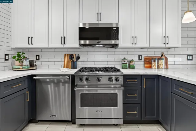 a kitchen with stainless steel appliances white cabinets and a stove top oven