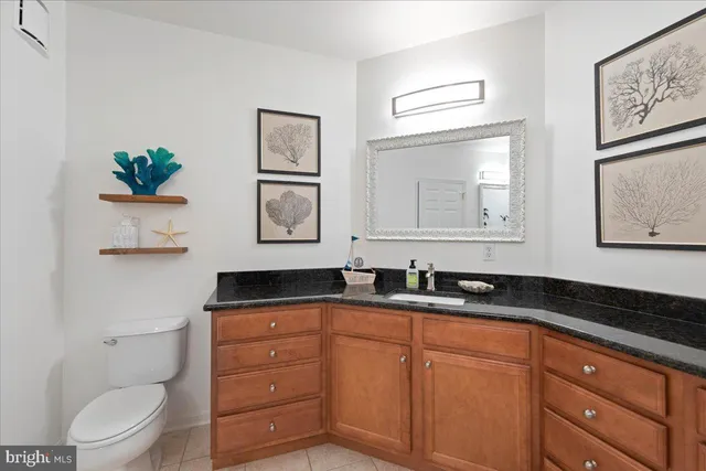 a bathroom with a granite countertop sink a toilet and mirror