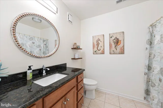 a bathroom with a granite countertop sink mirror vanity and toilet